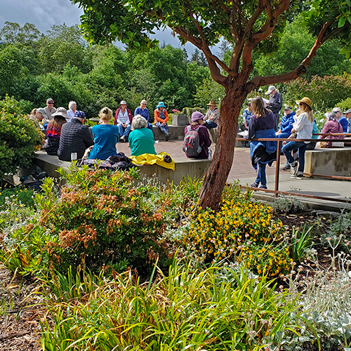 Individuals from various backgrounds sitting together on a bench in a park, fostering dialogue and learning in an educational setting.