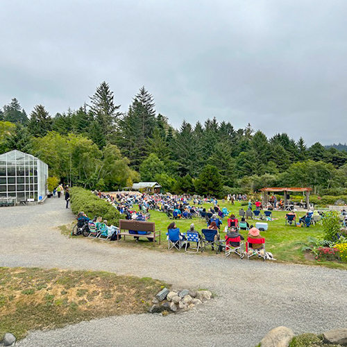 People gather in lawn chairs for an outdoor concert, celebrating the Summer Music Series with music and camaraderie.